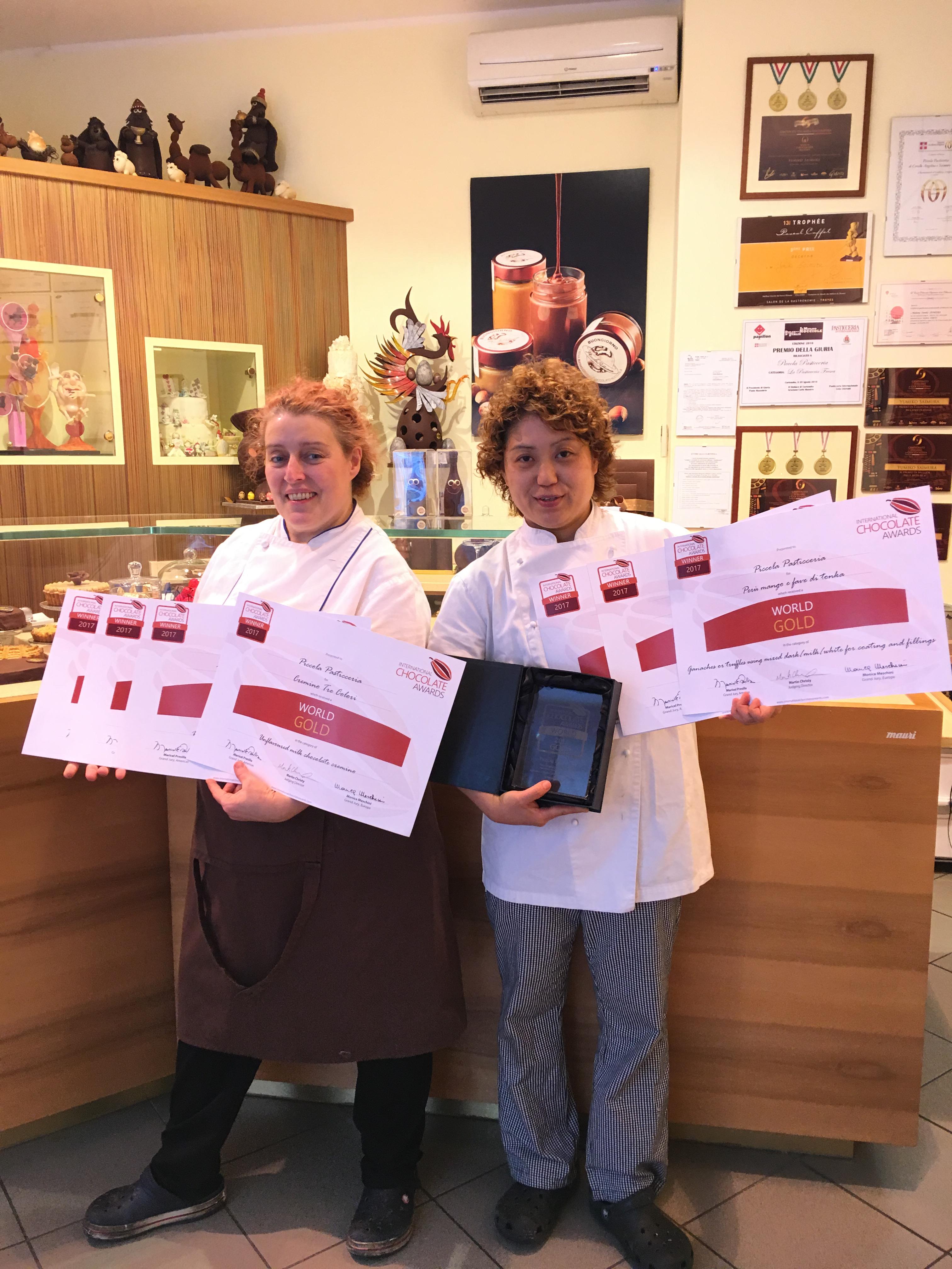 お店「ピッコラパスティチェリア」で撮影されたサイムラシェフとアンジェリーナさん インターナショナルチョコレートアワード世界大会での賞状とボンボンショコラ部門優勝のクリスタルの盾を持って。 抱えきれないほどの賞を一度に受賞してしまう、望んでもできないことなのですが、サイムラシェフの実力が正しく評価されるのは嬉しいことですね。